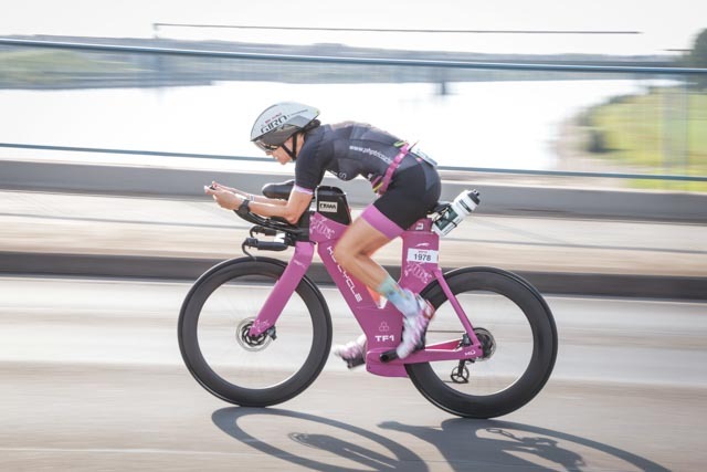 Female triathlete in aero position racing during the Ironman bike leg in Duisburg